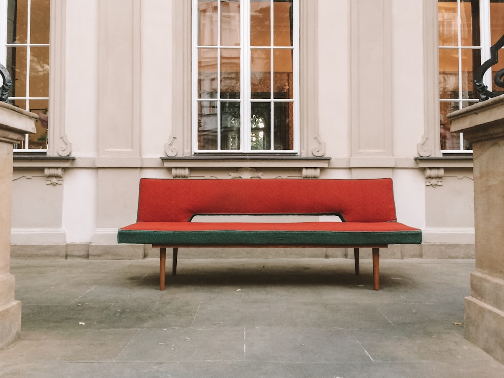 vacant red and green fabric armless futon outside white concrete building