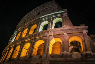 A dramatic sunset view of the Colosseum with golden light highlighting its ancient arches.