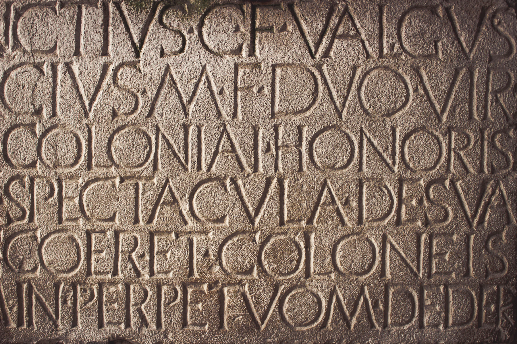 Rows of deep-cut Roman capital letters filling a stone slab, the words separated by small dots