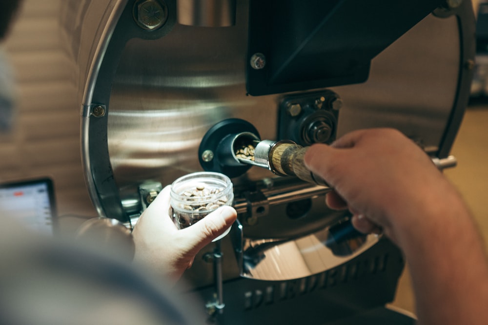 person pouring coffee beans inside commercial coffeemaker