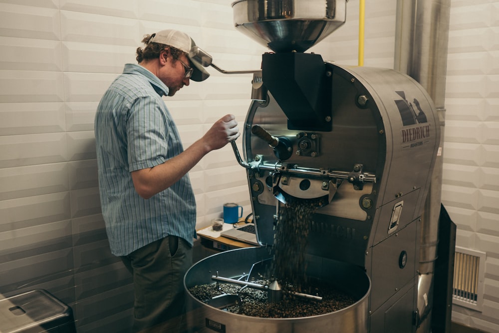 man in blue collared shirt operating gray and blue machine