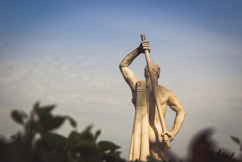 shallow focus photo of person holding rod statue