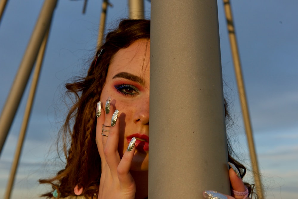 woman hiding half her face behind gray post