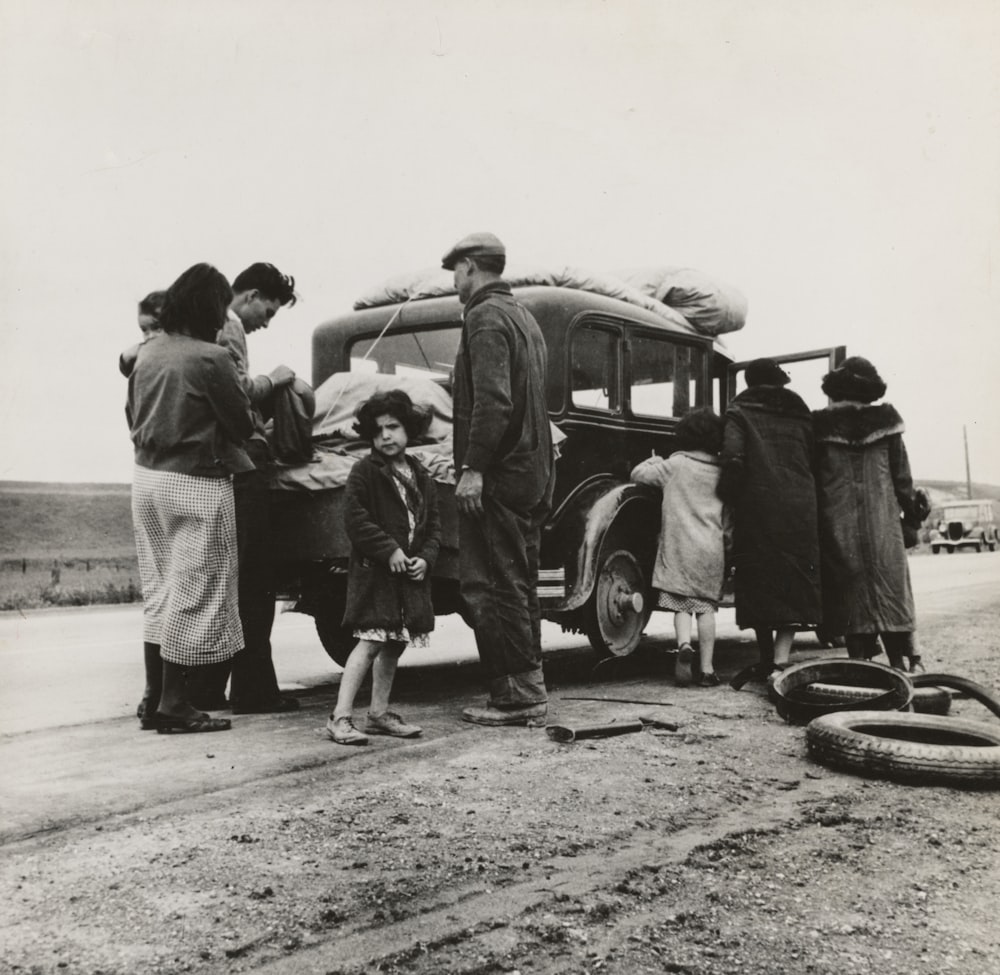 grayscale photography of people near vehicle