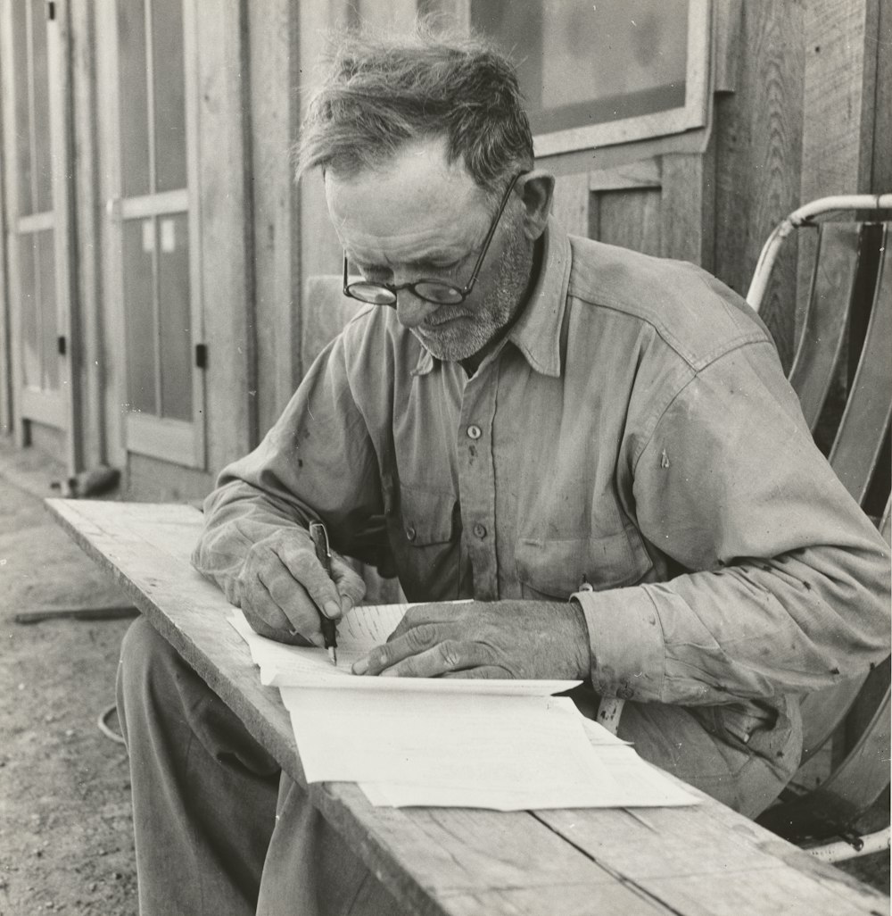 grayscale photography of man writing outdoors