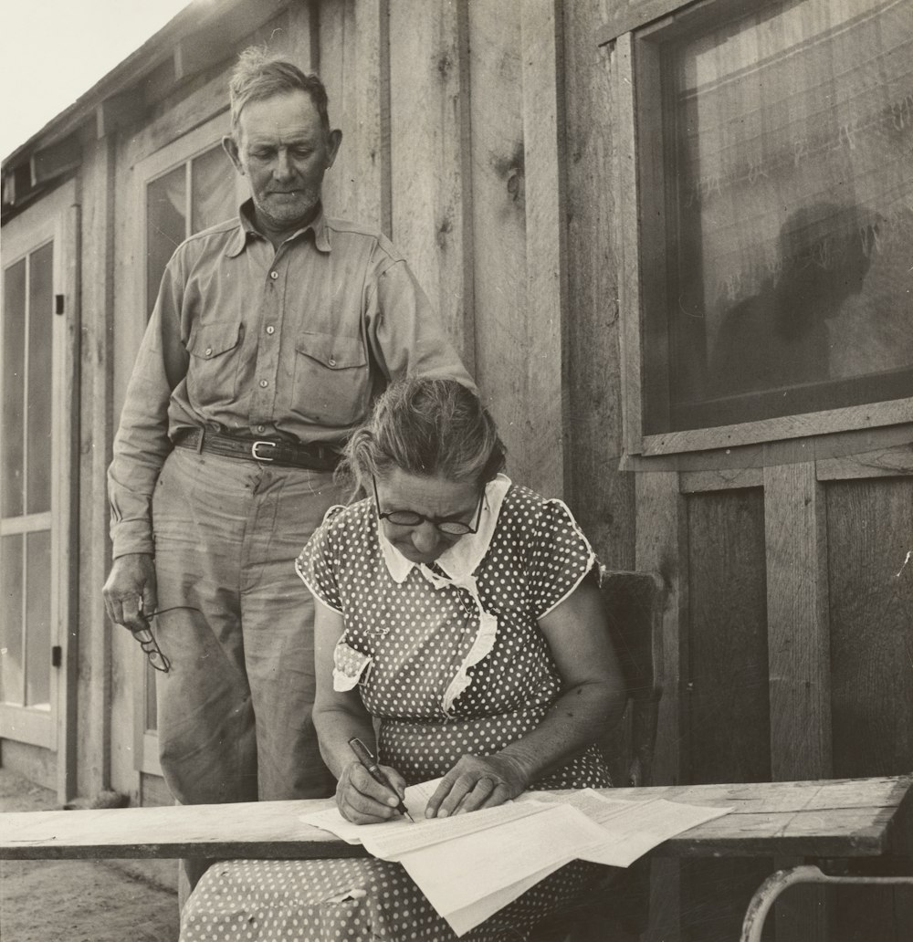 grayscal photo of man standing beside woman