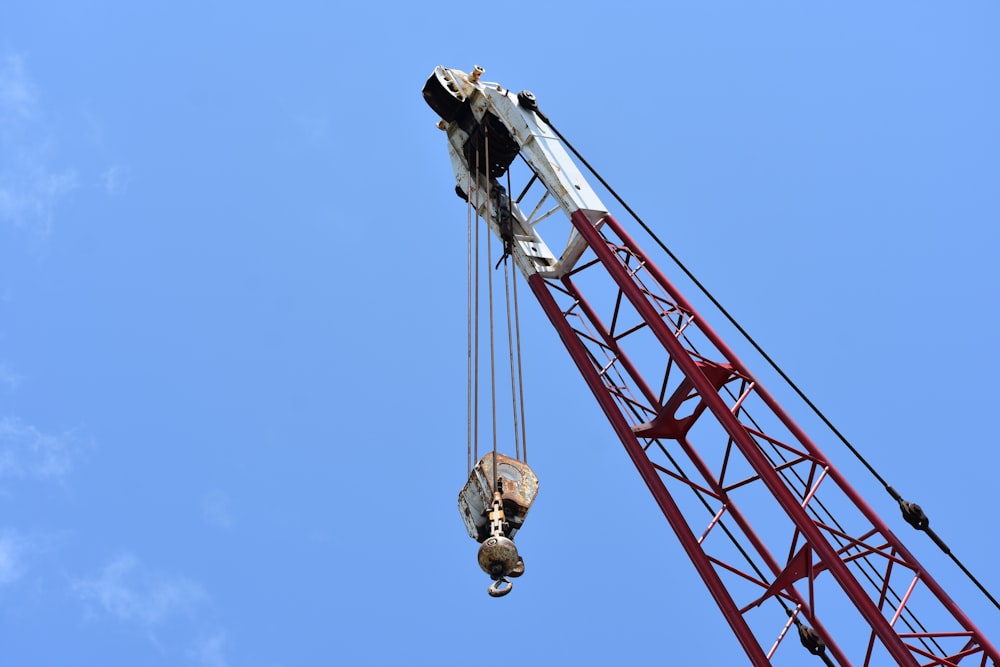 red and white crane pulley under blue sky