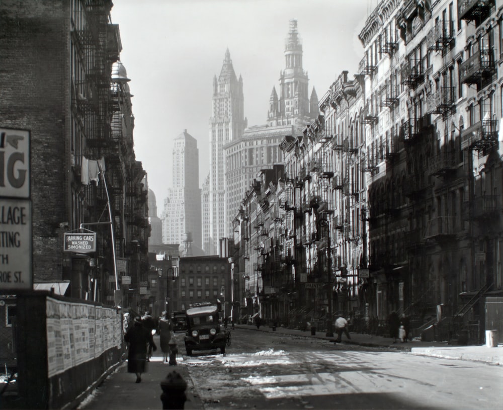 grayscale photography of people walking near road viewing high-rise buildings