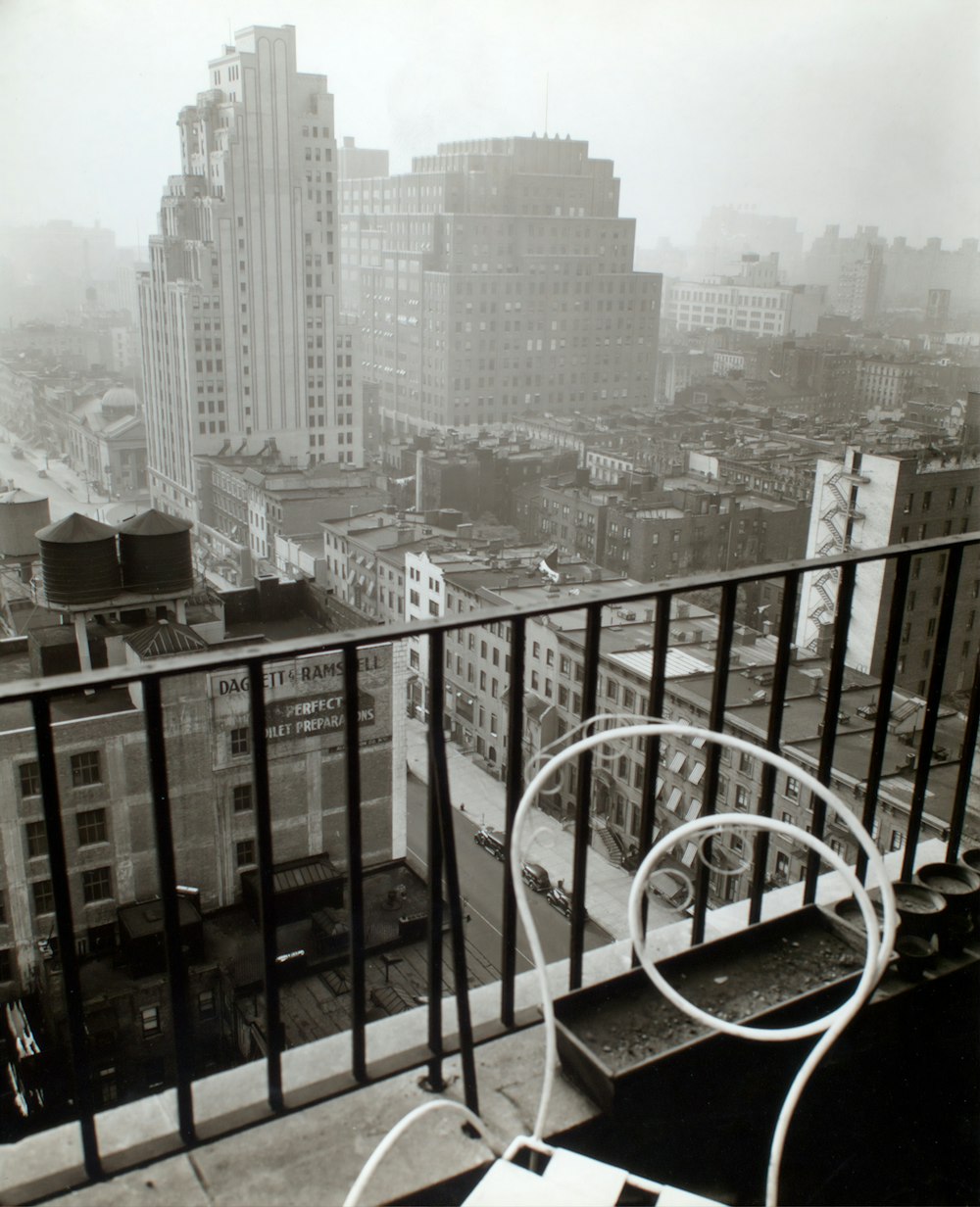 grayscale photography of vehicles on road viewing city with high-rise buildings