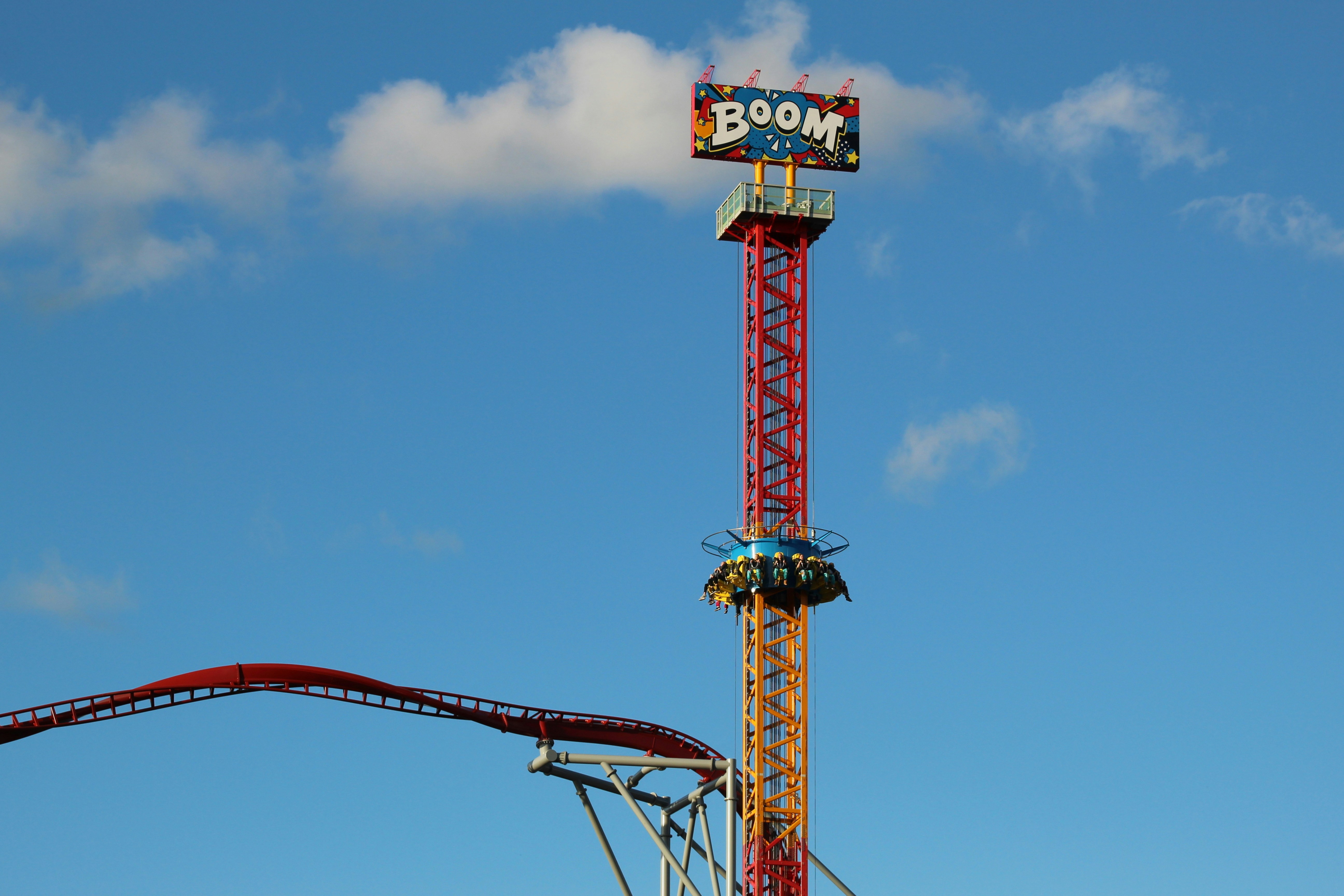 Red and blue Boom amusement part ride under blue and white skies during ...