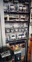 An electrical switchgear panel with multiple circuit breakers and wiring is organized within a metal frame. Colored wires are neatly attached, and labels or indicators can be seen on some components. The environment suggests an industrial or technical setting.