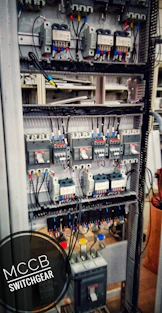 Photo of a skilled electrician installing a complex electrical panel in an industrial setting.