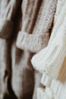 A row of artisanal baby alpaca sweaters hanging, showing intricate knit patterns in warm hues