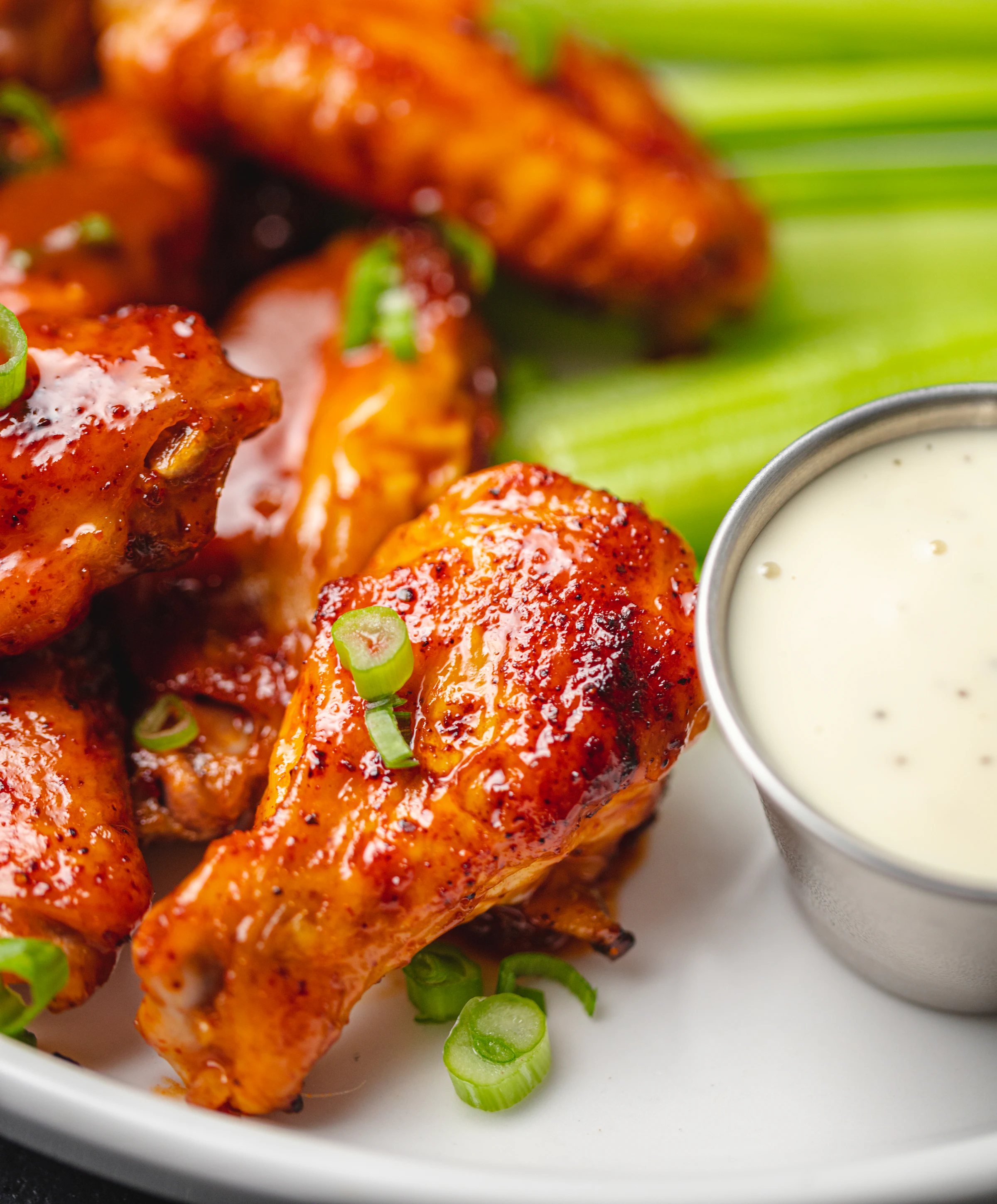 Buffalo wings glistening with sauce, served with celery and dip.