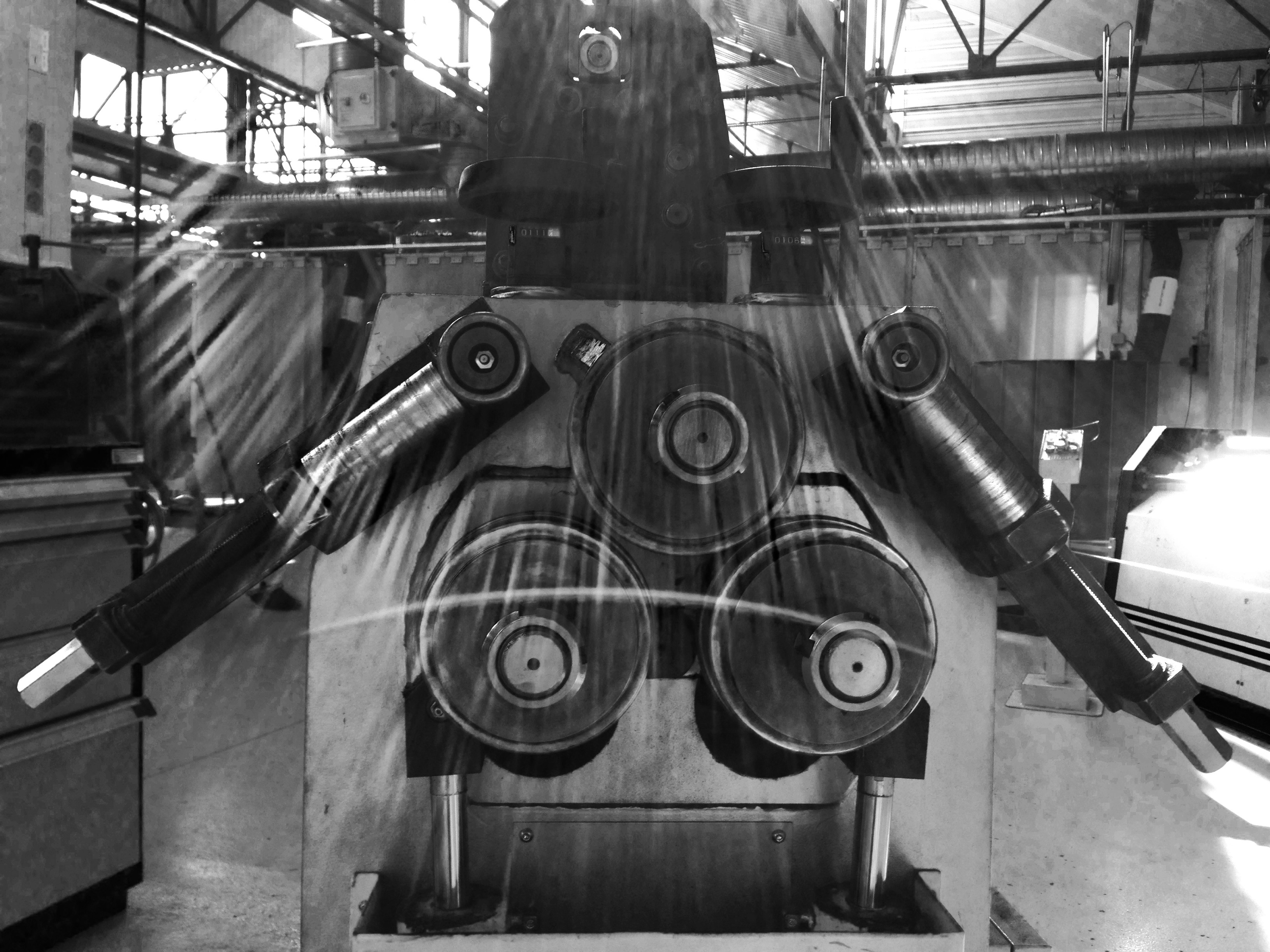 Paper manufacturing mill with large industrial rollers and machinery in bright factory