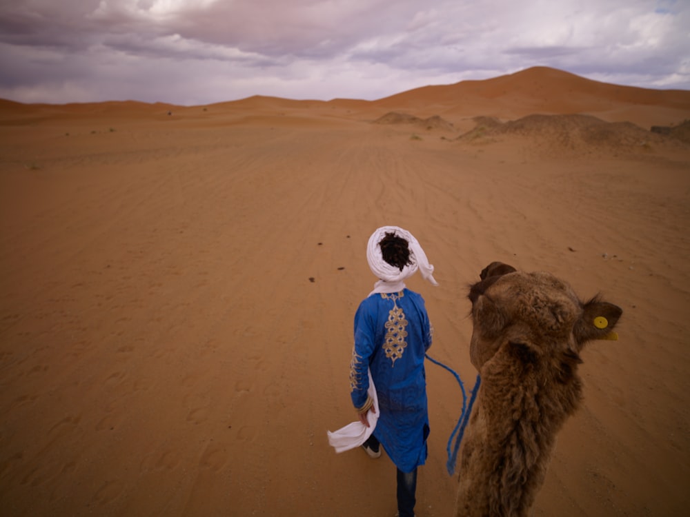 person walking beside camel