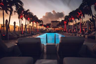 An elegant luxury resort poolside at dusk, glowing softly with ambient lighting.