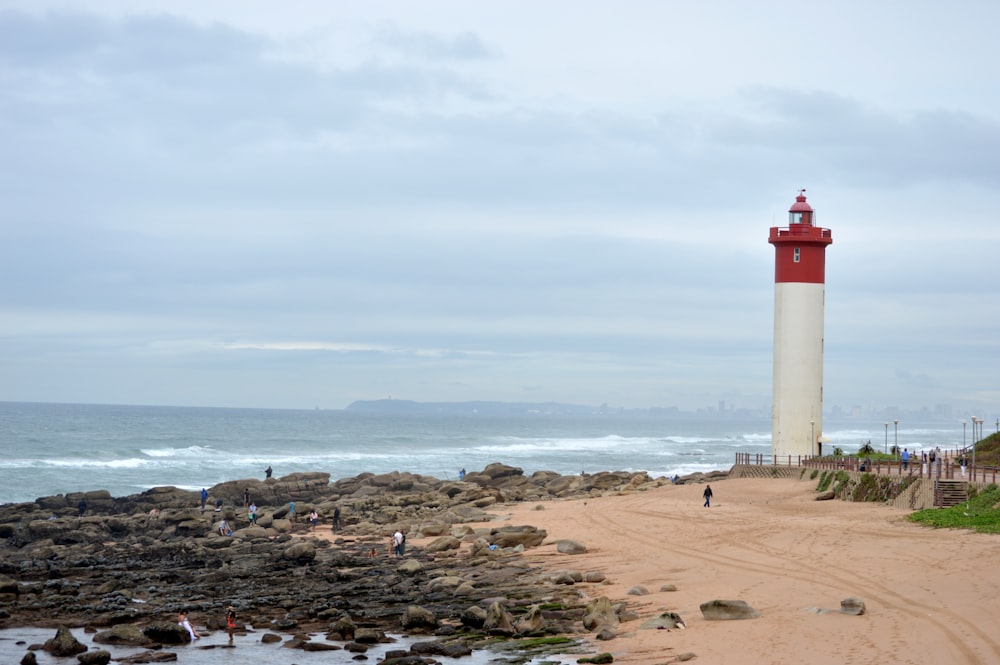 white and red lighthouse near body of water