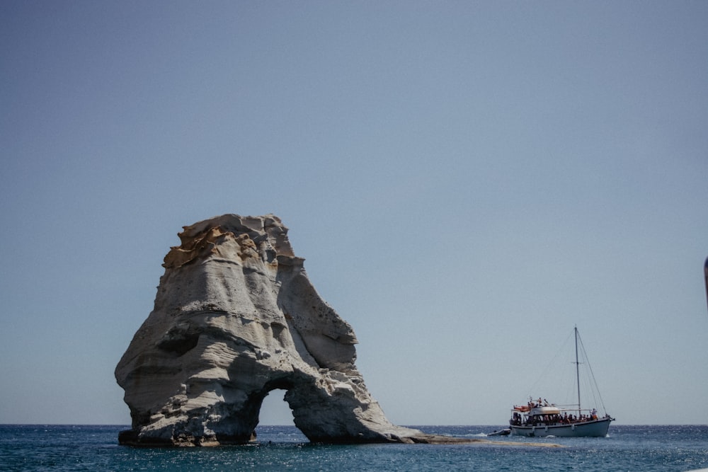 boat by rock formation at sea during daytime