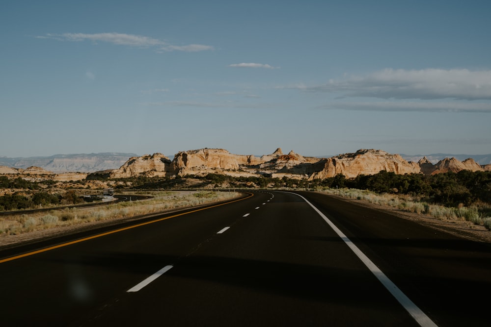 concrete road beside field of soil and mountains