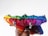 A collection of colorful zippered pouches, each in a different vibrant hue, is held together. The pouches are arranged in a rainbow sequence with visible zippers and metallic pull tabs, and are being held in a hand with a dark skin tone.