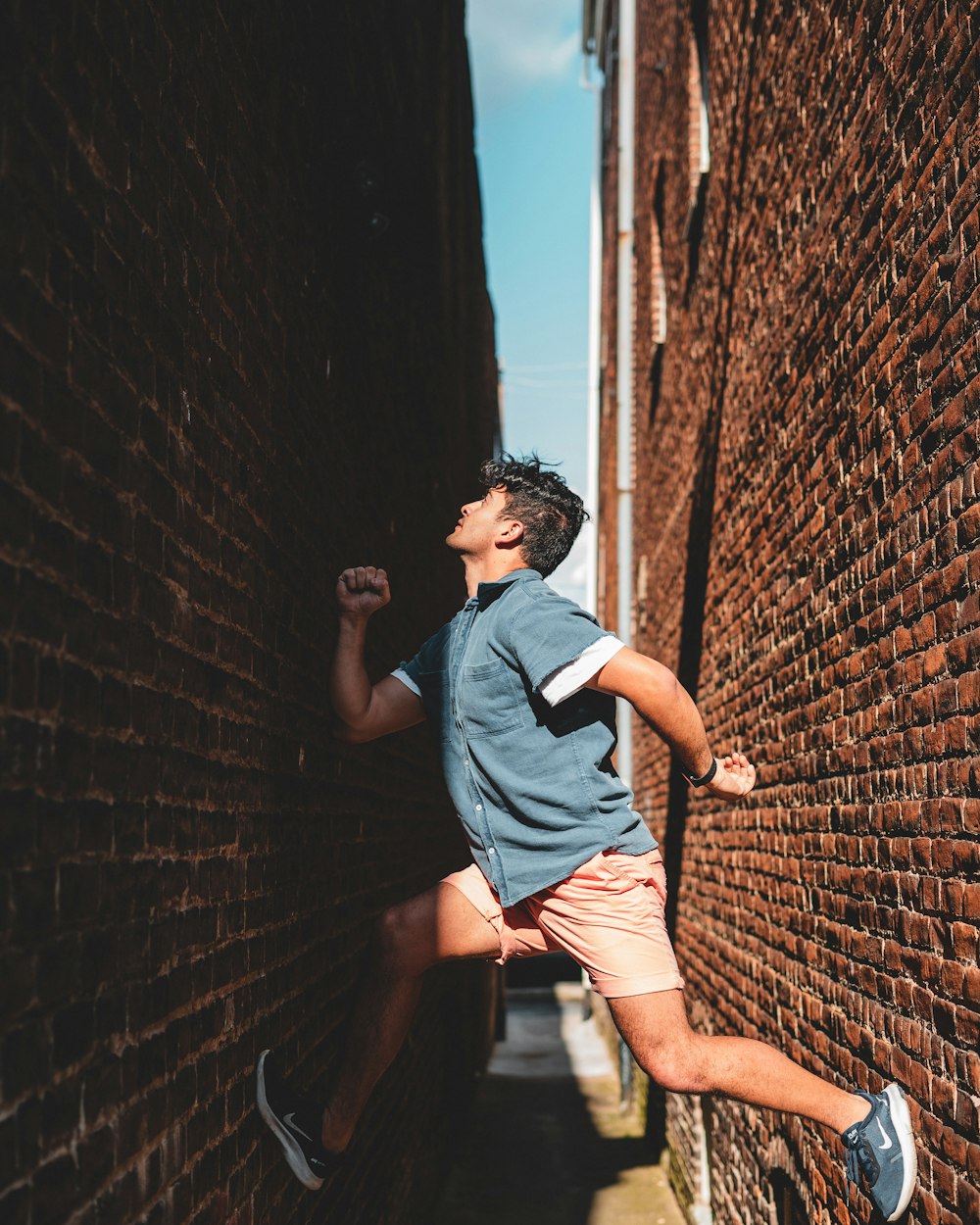 a man running down a street next to a brick wall