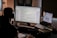 A focused trader analyzing data on multiple screens in a dark-themed workspace.