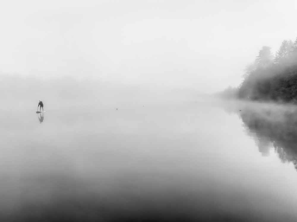 a person standing on a surfboard in the middle of a lake