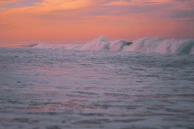 An acrylic seascape capturing waves crashing under a glowing sunset sky.