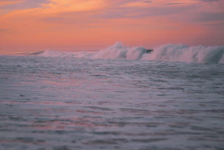 An acrylic seascape capturing waves crashing under a glowing sunset sky.