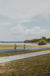 Two boys smiling together, backpacks on, ready for an adventure in a sunny park.