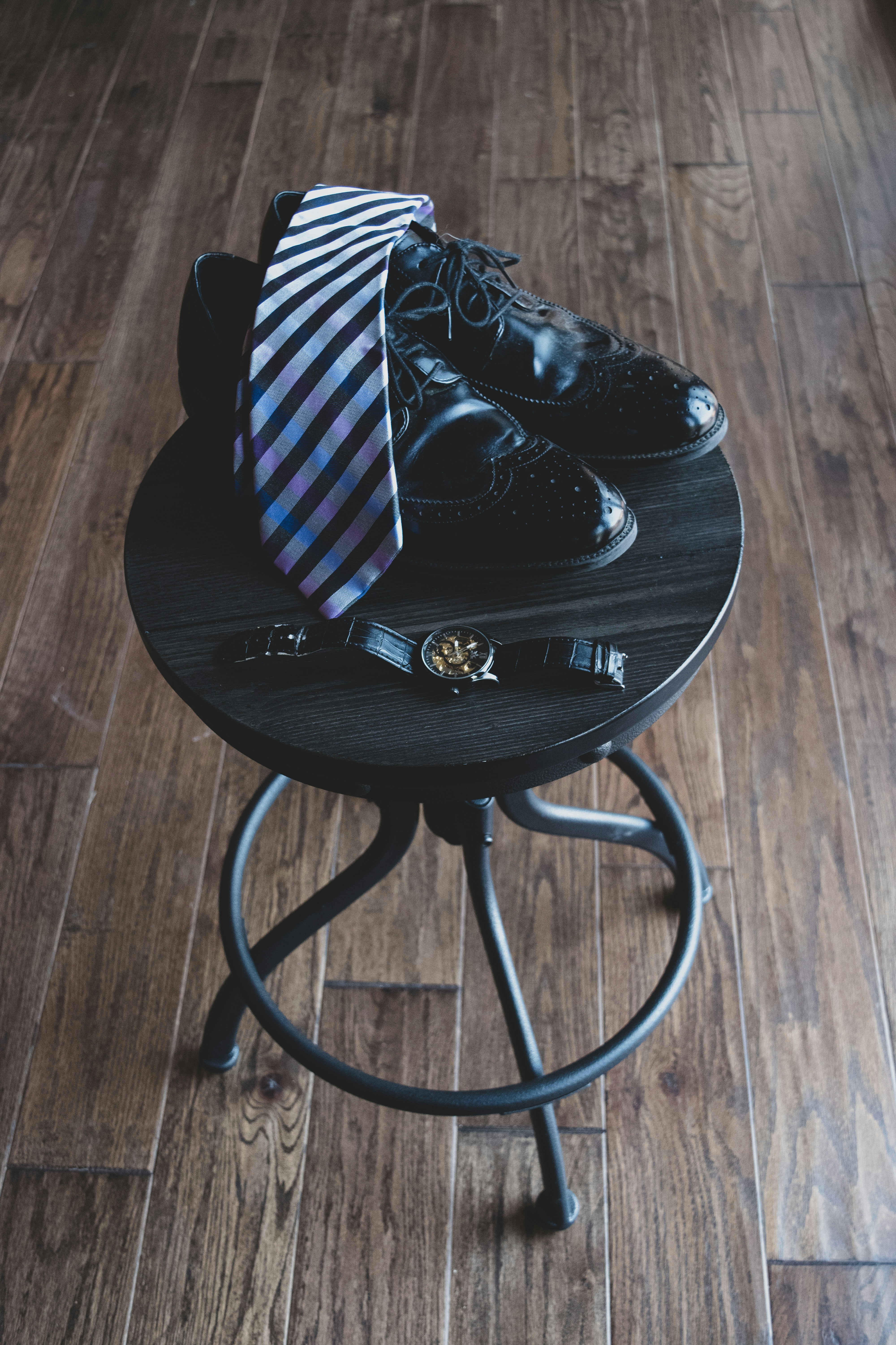 black and white striped necktie on pair of black oxford shoes