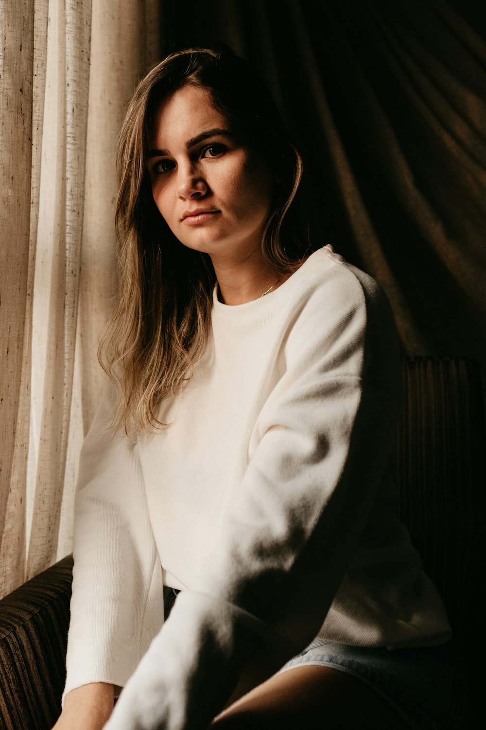 woman in white sweater sitting indoors