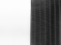 A solar panel with a sleek design is split into two halves. The left side is a clean white surface, while the right side features a pattern of dark vertical lines representing the photovoltaic cells.