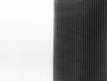 A solar panel with a sleek design is split into two halves. The left side is a clean white surface, while the right side features a pattern of dark vertical lines representing the photovoltaic cells.