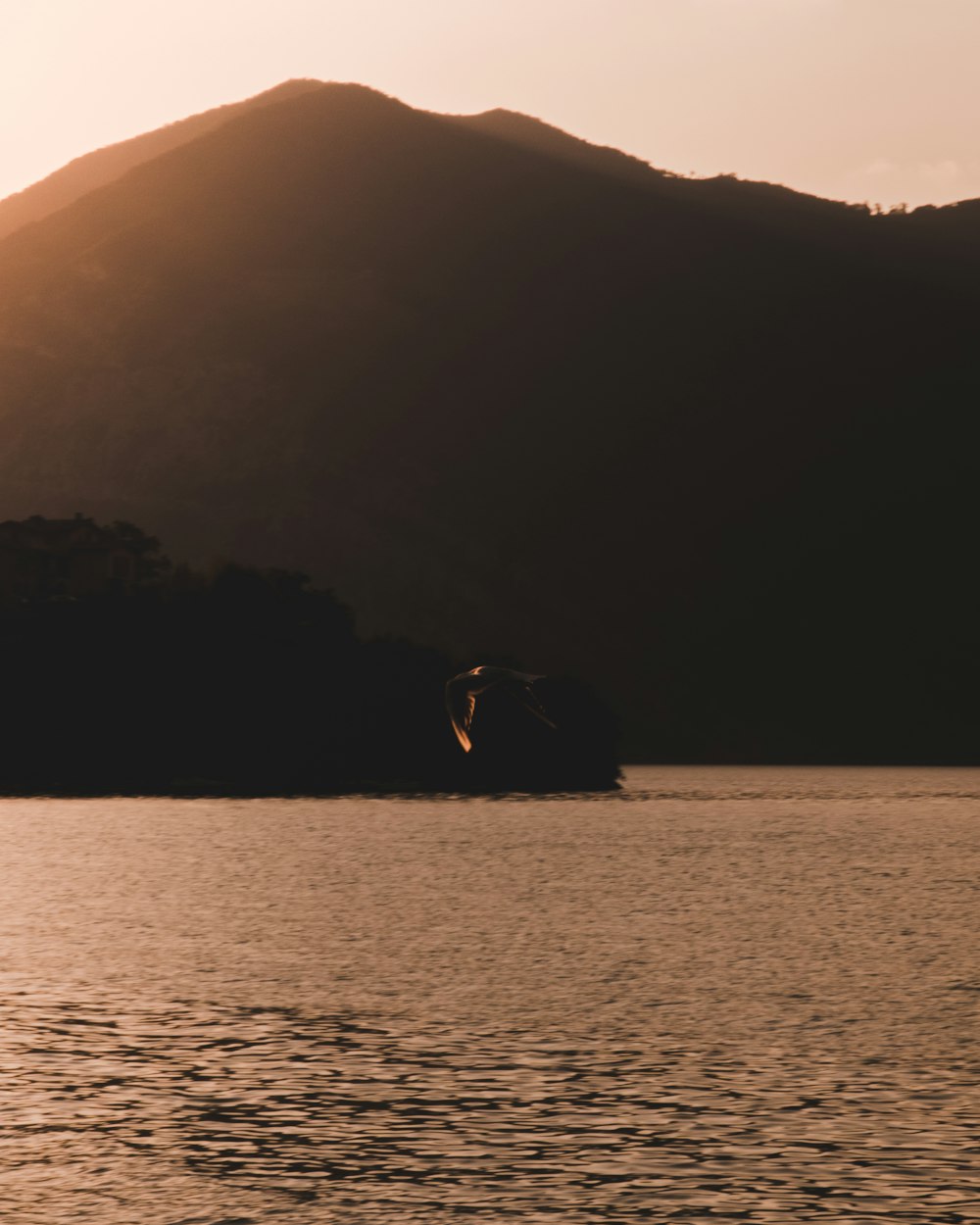 body of water near mountain at golden hour