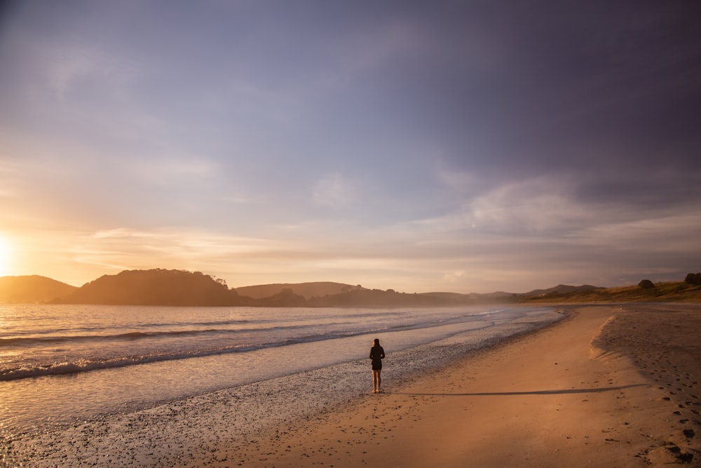 a person standing on a beach at sunset