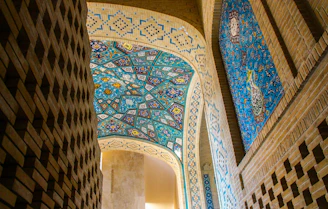A corridor with blue and white mosaic flooring, walls adorned with vibrant contemporary artworks.