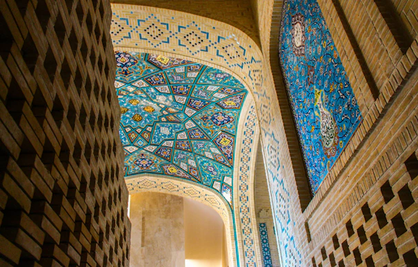 A corridor with blue and white mosaic flooring, walls adorned with vibrant contemporary artworks.