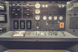 Control panel with switches and gauges in a power plant setting.