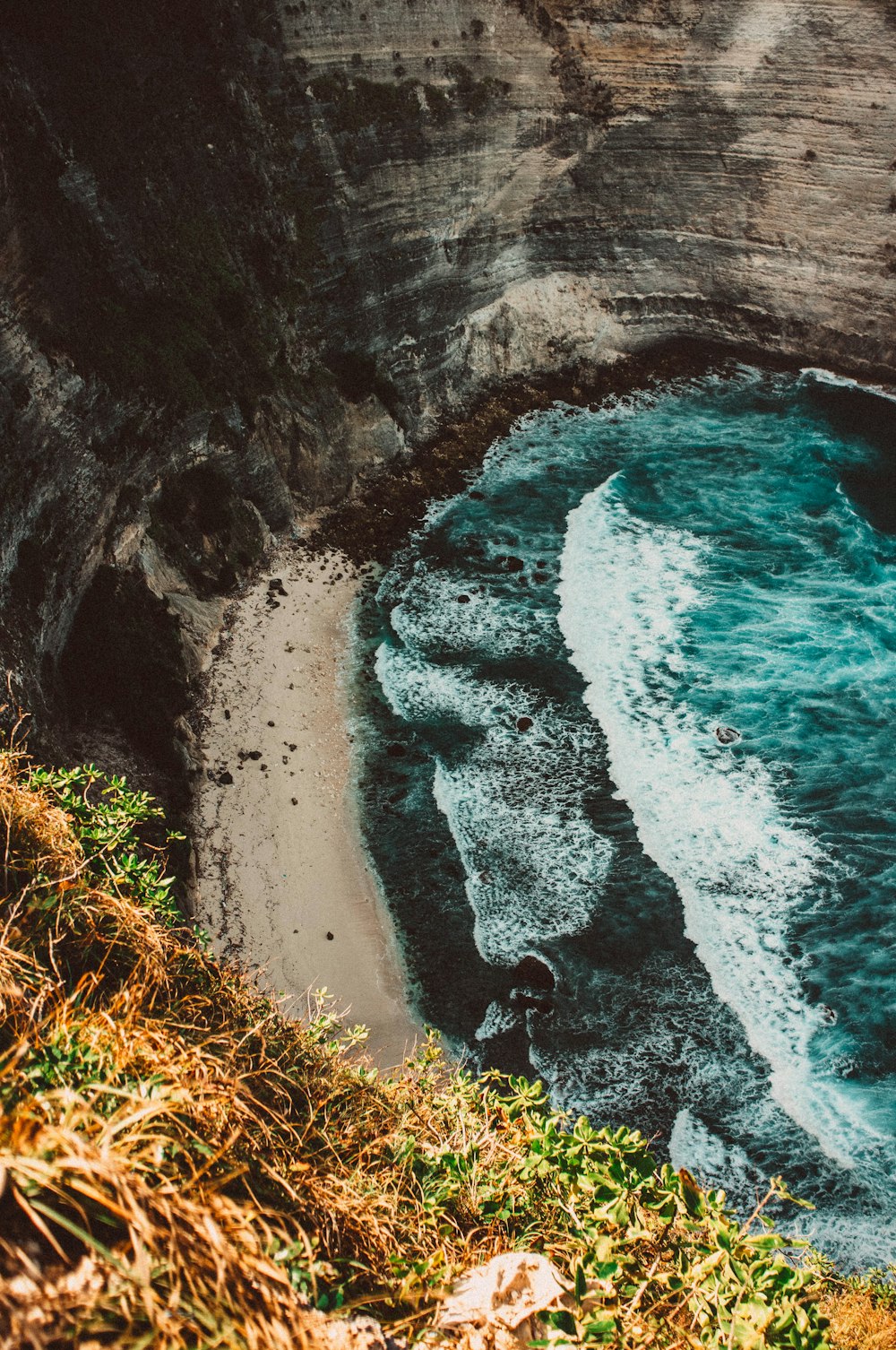 una playa junto a un acantilado con un cuerpo de agua