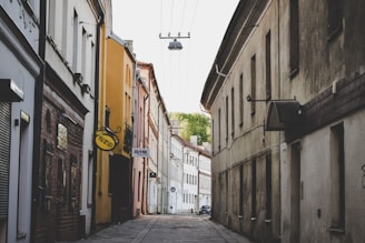 a narrow street with a yellow sign hanging from the side of it