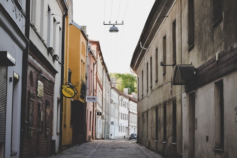 a narrow street with a yellow sign hanging from the side of it
