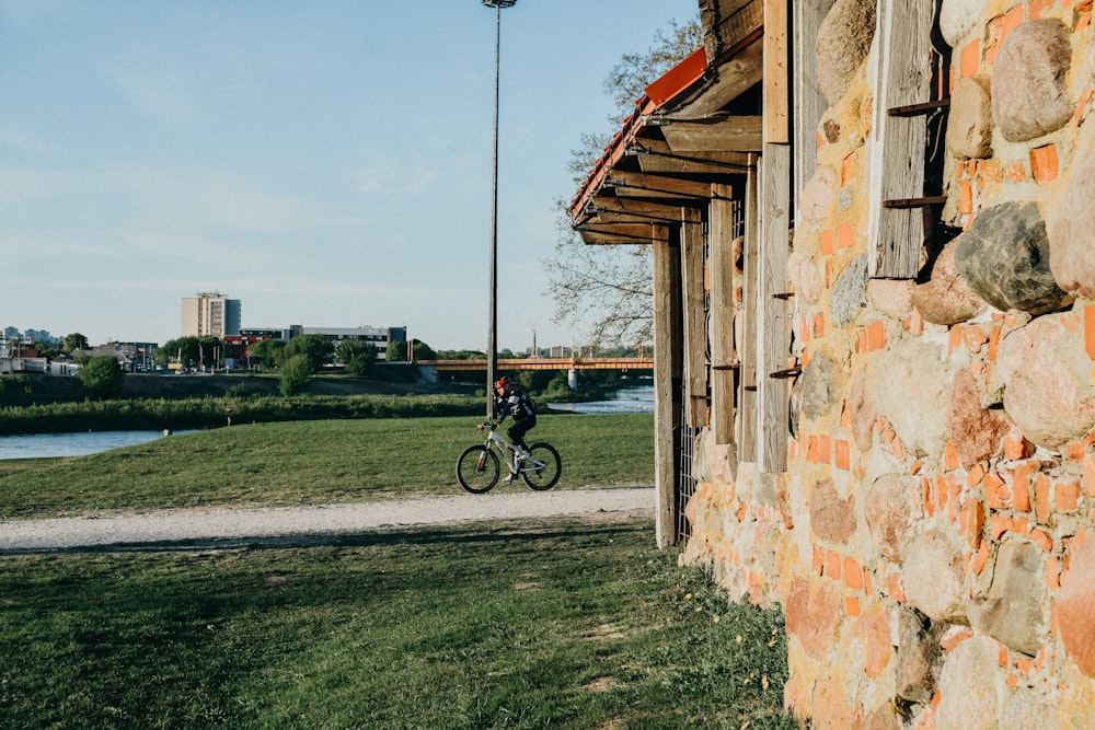 Person, die tagsüber in der Nähe der grünen Wiese Fahrrad fährt