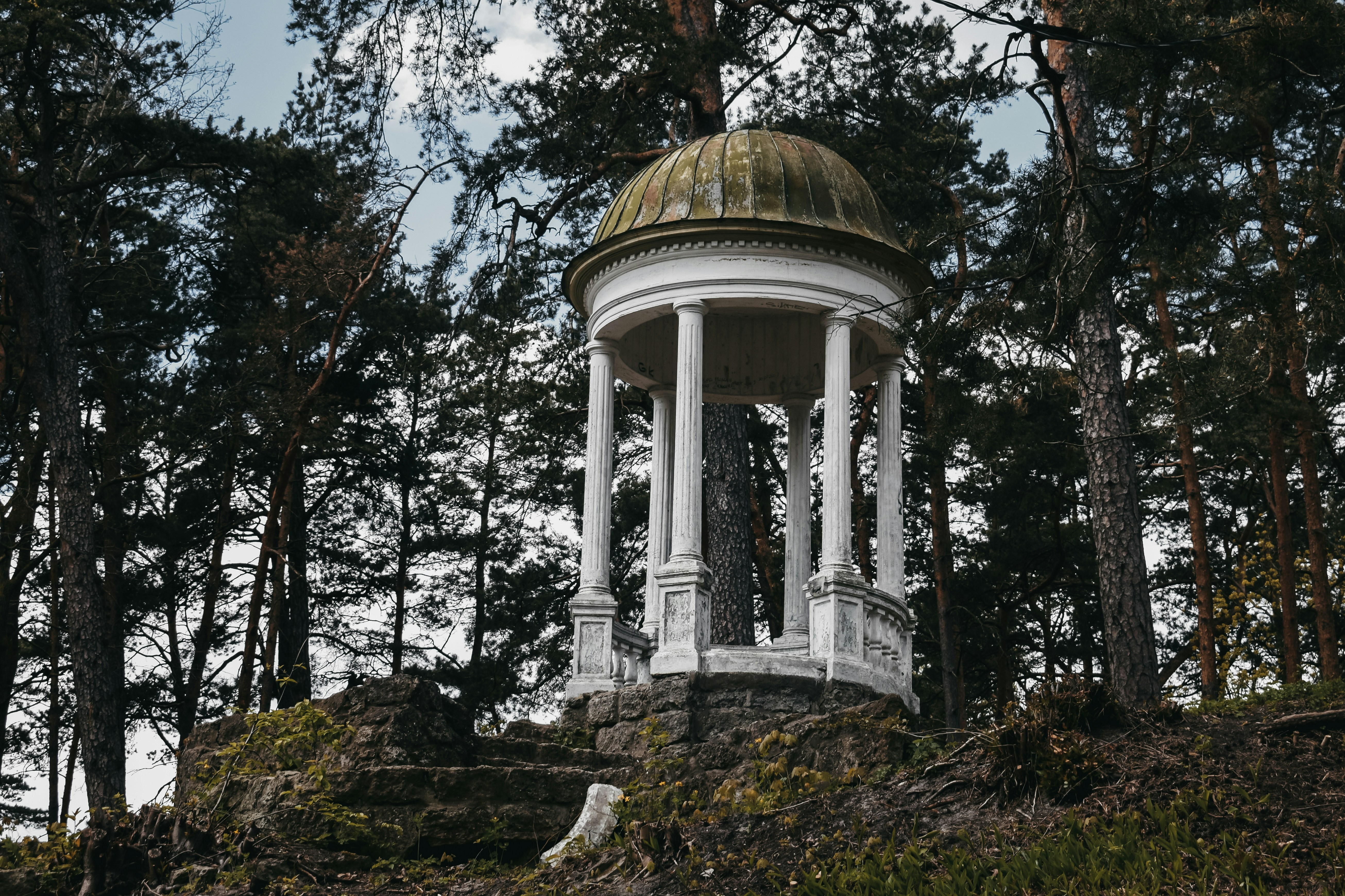 a white gazebo sitting on top of a lush green hillside