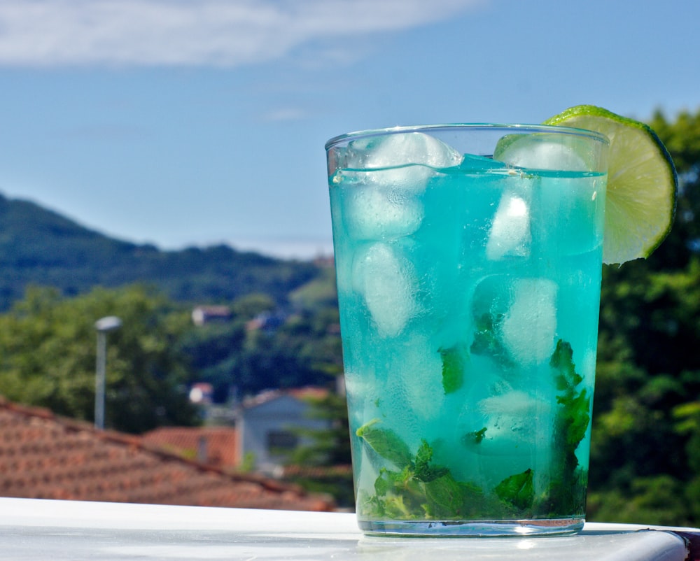 a tall glass filled with ice and a lime slice