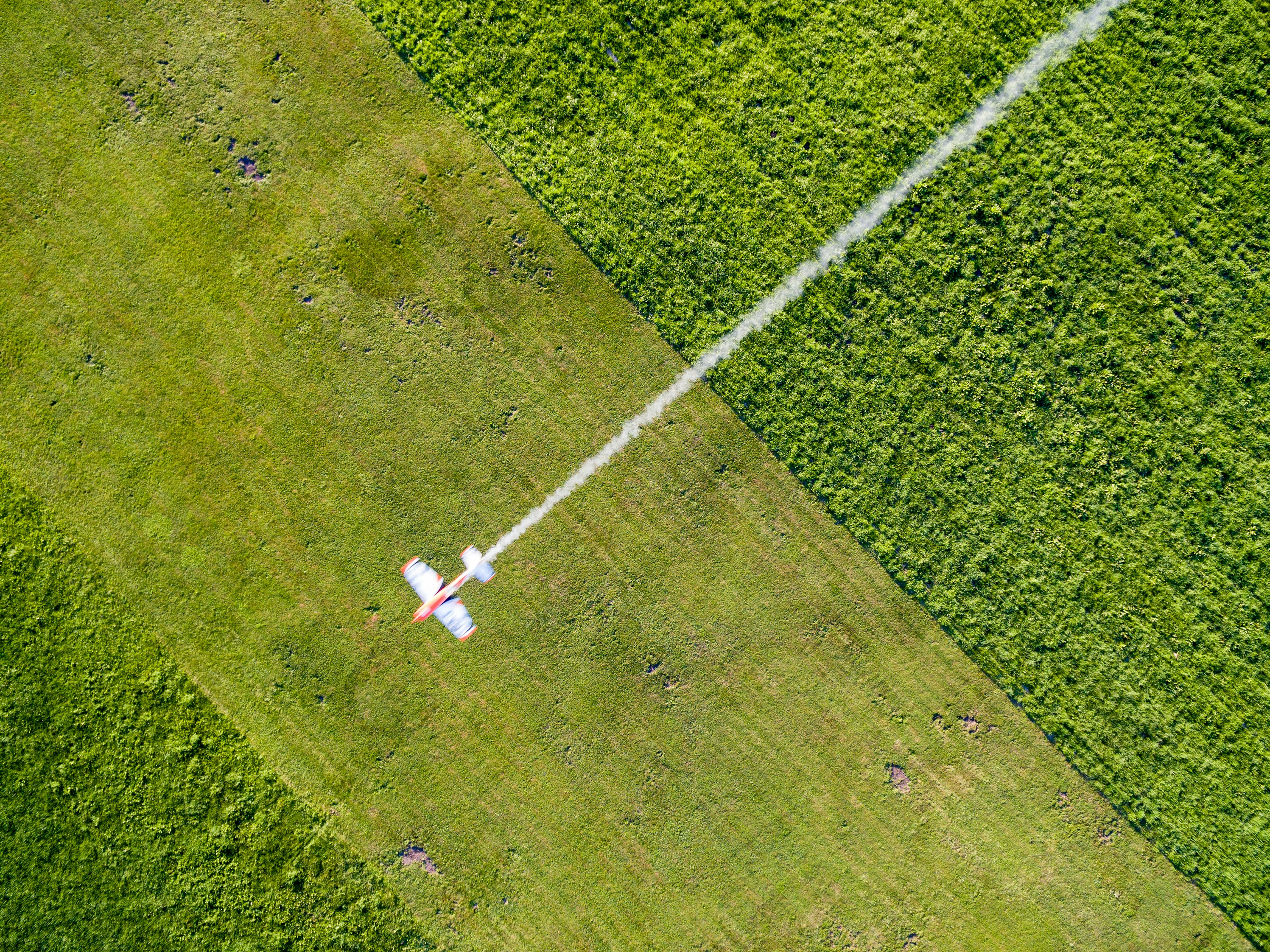 an aerial view of a field with a jet flying over it