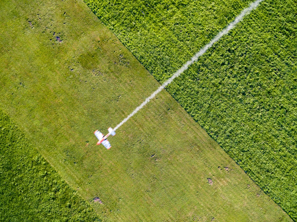 an aerial view of a field with a jet flying over it