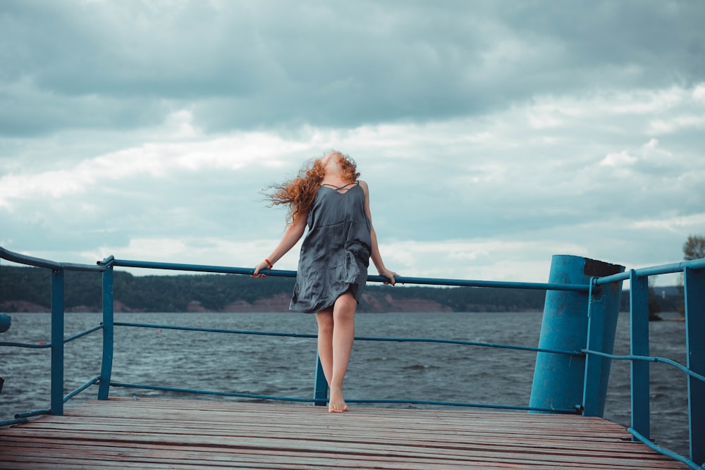 woman standing on dock and bending her body during daytime