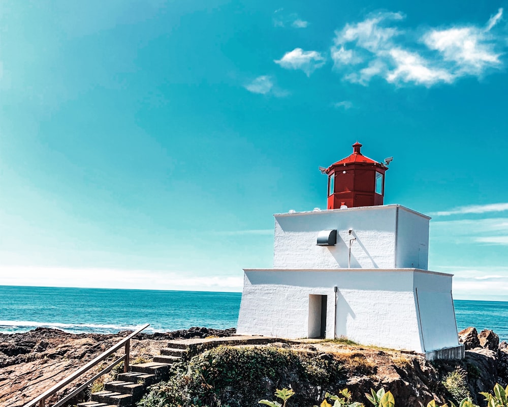 red and white lighthouse on rock